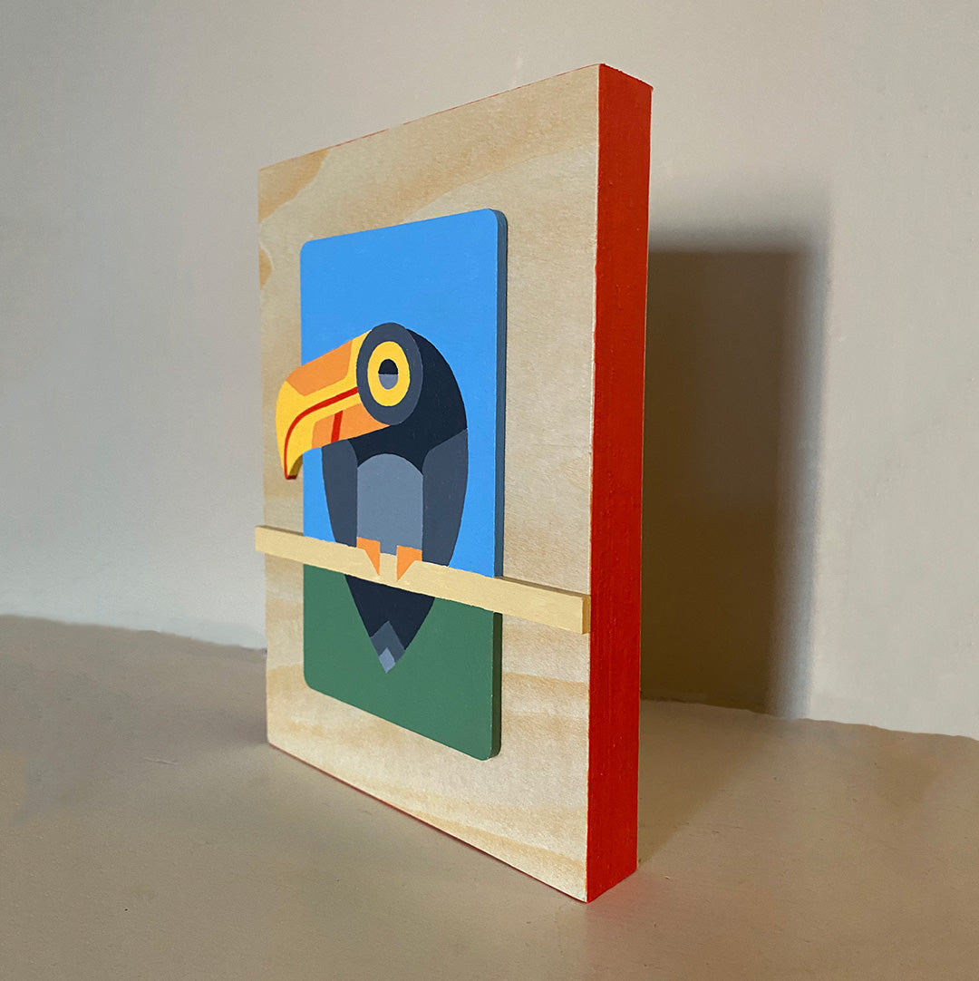 Wooden panel with red painted edges, and a dimensional, colorful toucan geometric painting