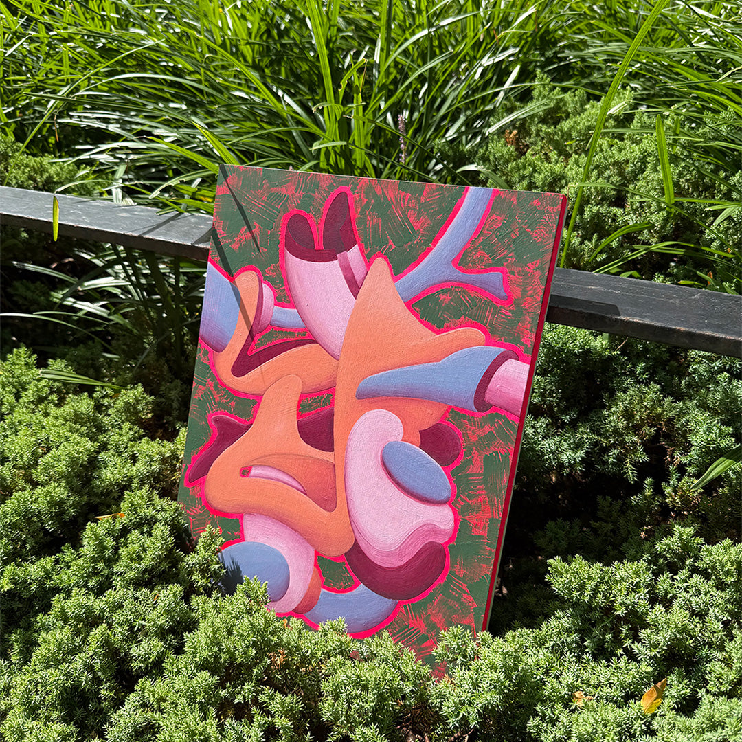 Abstract artwork with colorful shapes sitting amongst green plants outdoors