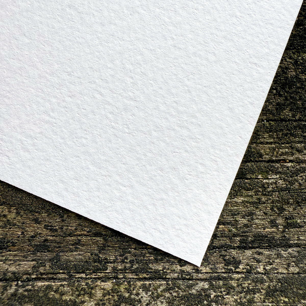 White cold press paper on a textured wood surface