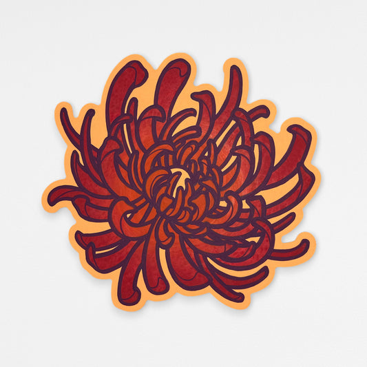 Handcrafted chrysanthemum wood wall sculpture with bright orange and coral red petals and dark purple outlines. Hanging on a white wall.