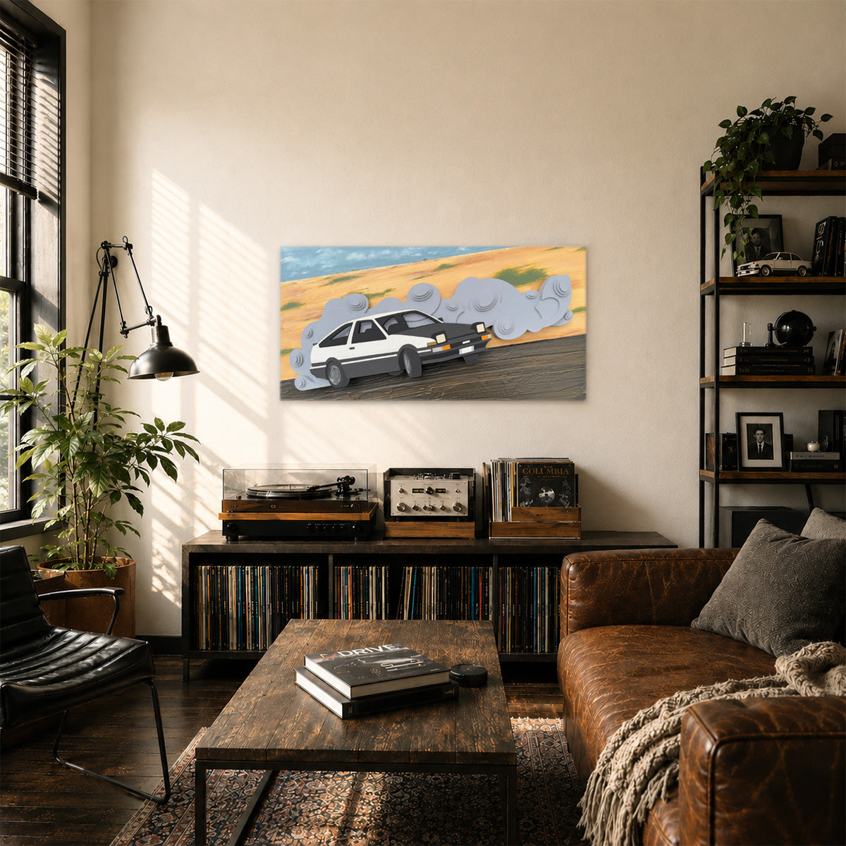 Layered wood wall art of a Toyota AE86 drift car driving through a desert track with layers of gray tire smoke, displayed on a beige wall in a modern, sunlit man cave with a leather sofa, record player, and plants.