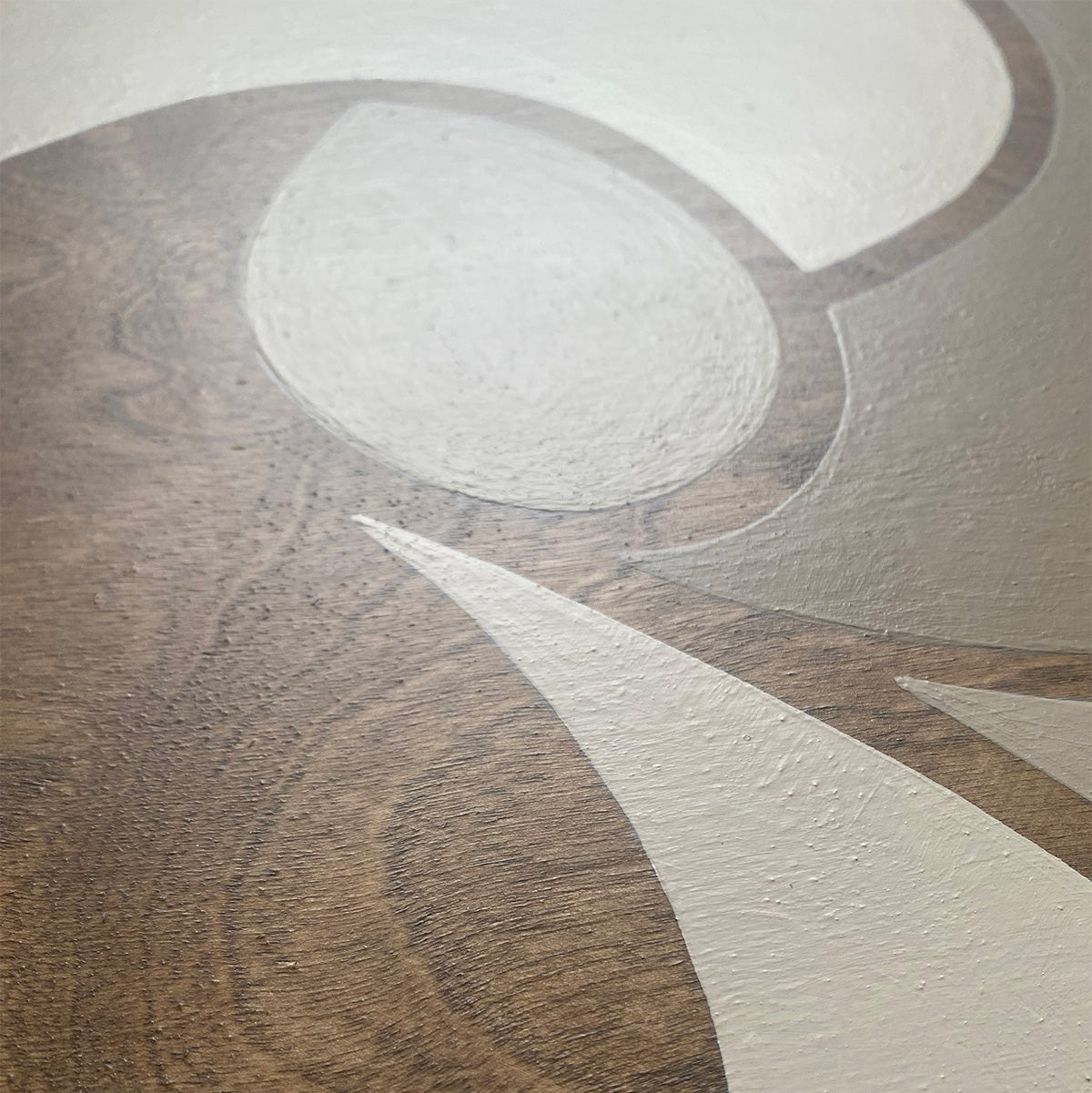 A close-up detailed photo of natural walnut stained wood grain art with beige and taupe painted organic color accents.