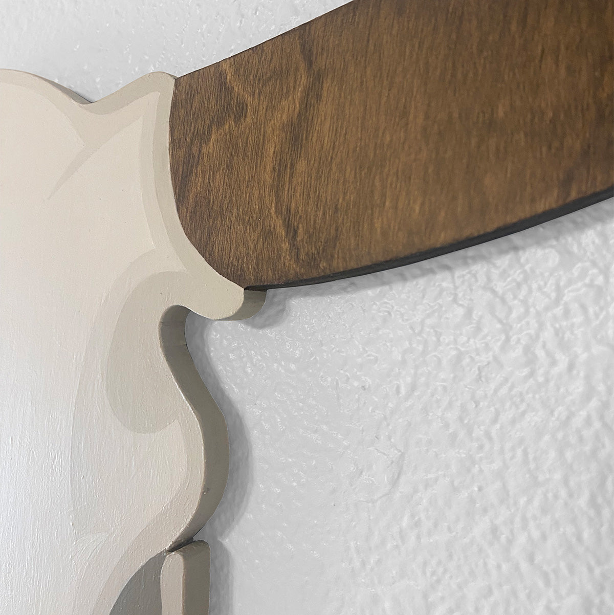 A close-up detail of walnut wood grain finished longhorn, and neutral cream painted skull gradient details set against a white wall.