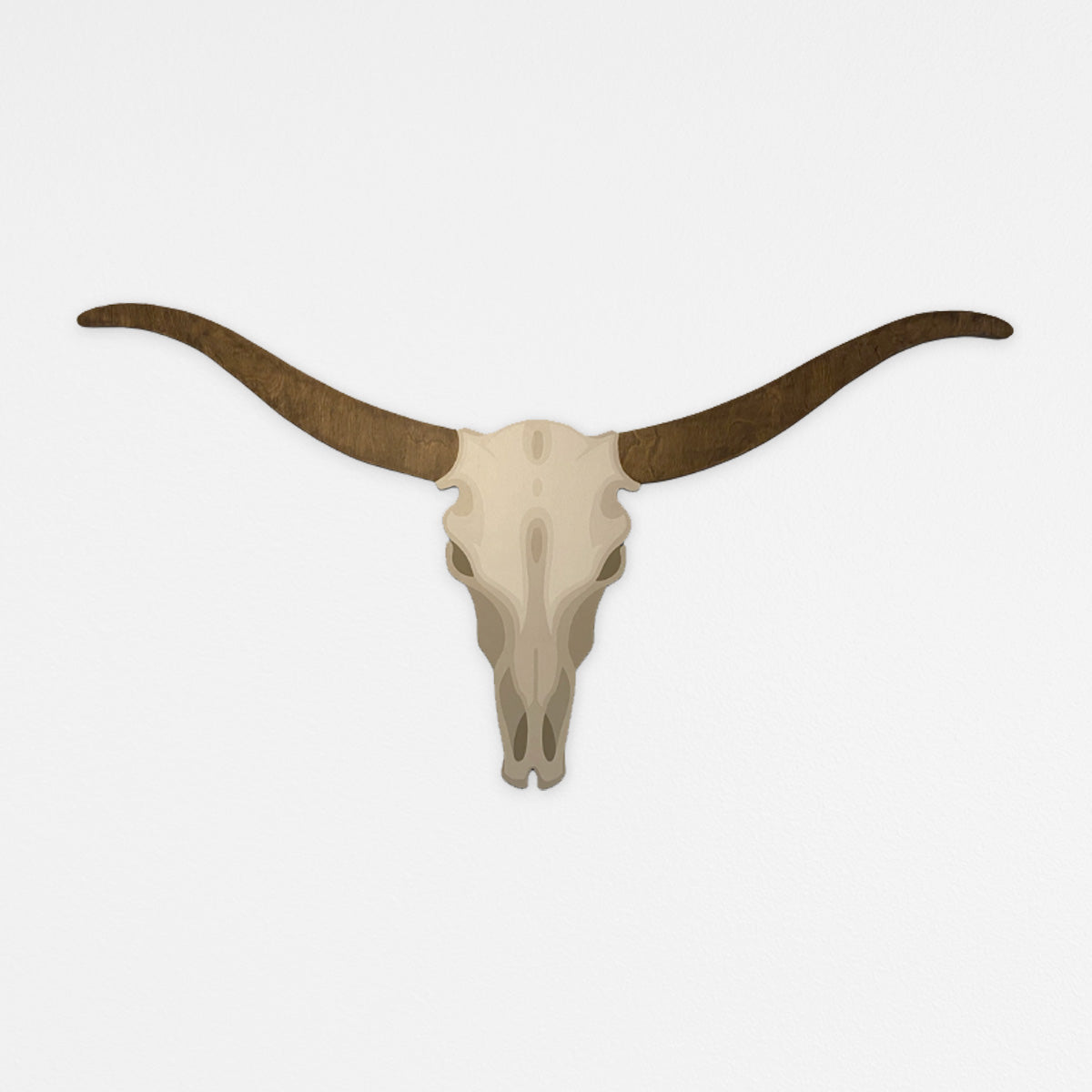 Handcrafted longhorn wood wall sculpture with neutral painted gradient skull, and natural walnut wood finish horns. Hanging on a white wall.