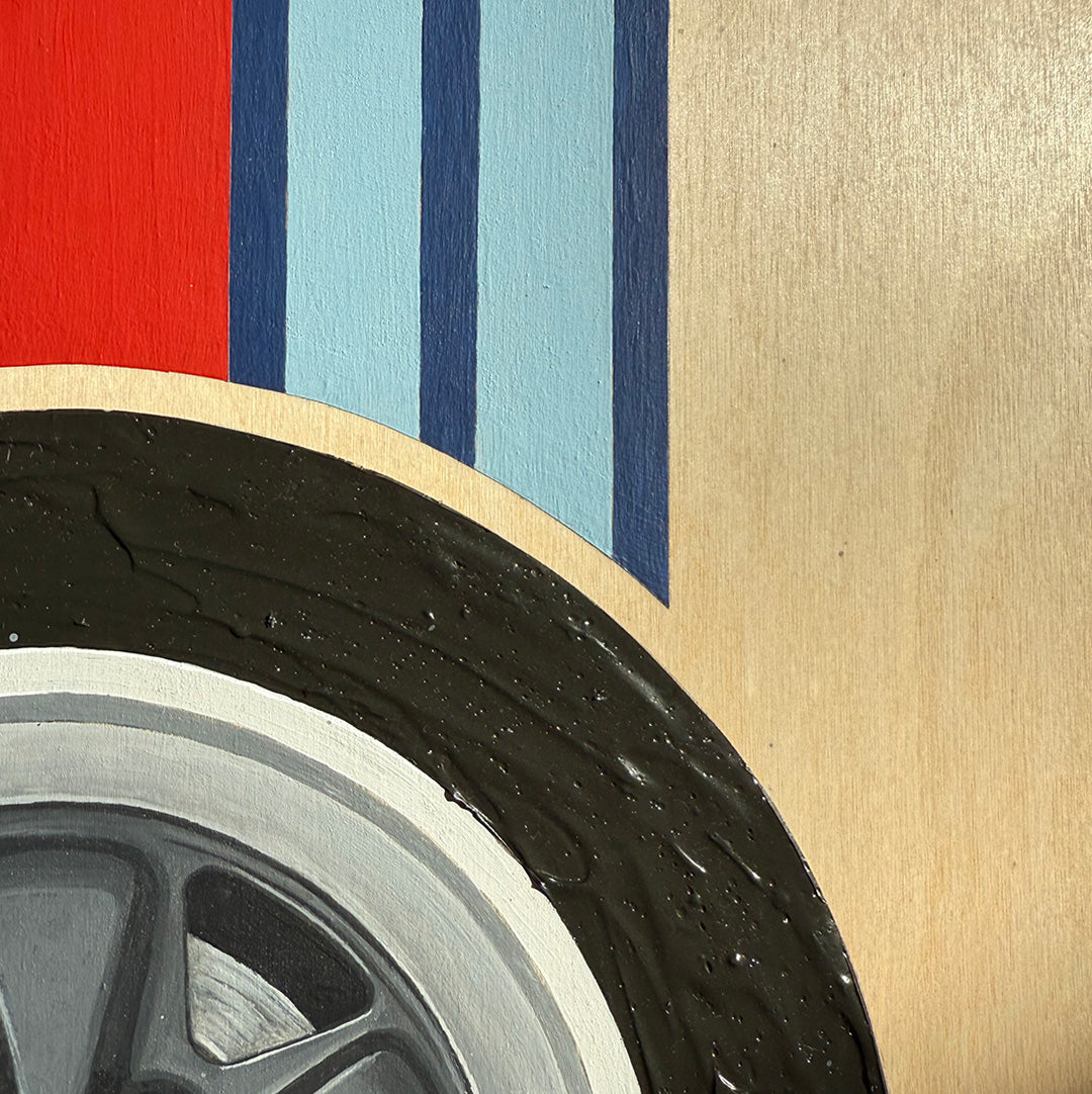 Close-up of a textured acrylic car tire with a colorful racing stripe pattern on a wooden surface