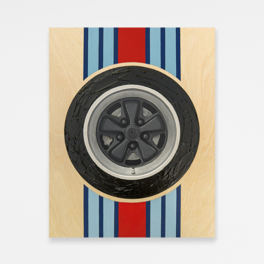 Hand-painted black porsche fuchs wheel wood wall art with textured tire and martini racing stripes behind the wheel. Hanging on a white wall.