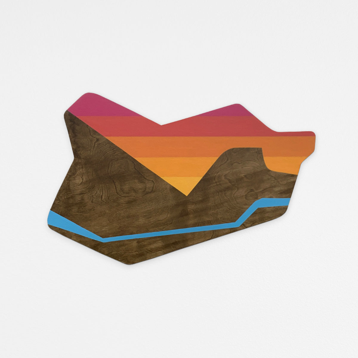 Handcrafted abstract wood wall sculpture with geometric walnut stained mountain range and a geometric stepped sunset gradient. Hanging on a white wall.